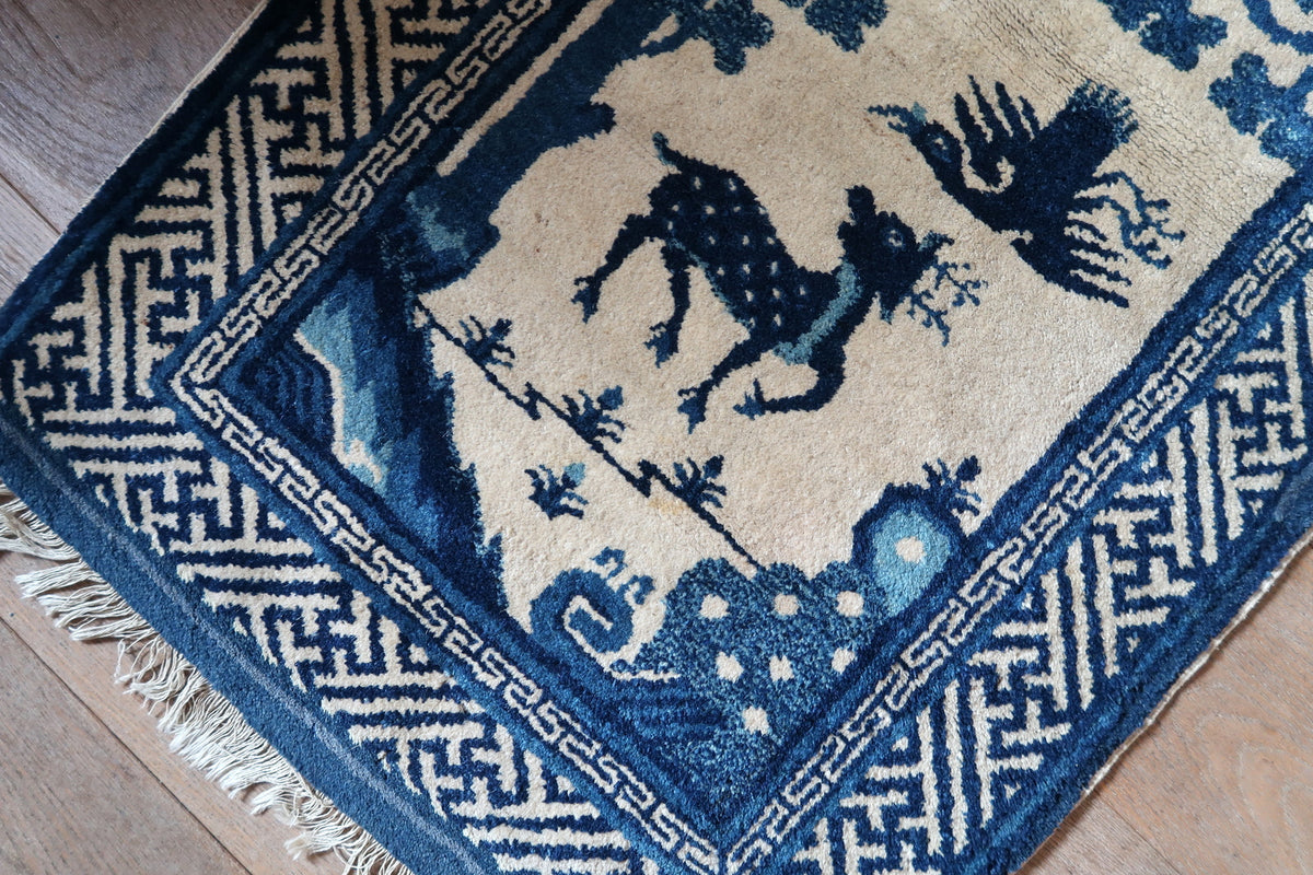 Angled end detail with spotted deer, flying bird, blue landscape and uneven light fringe