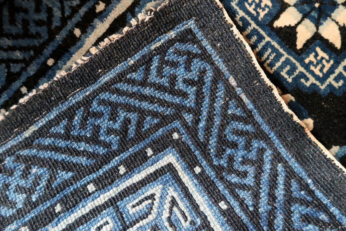 Folded rug corner showing reverse weave and blue geometric border