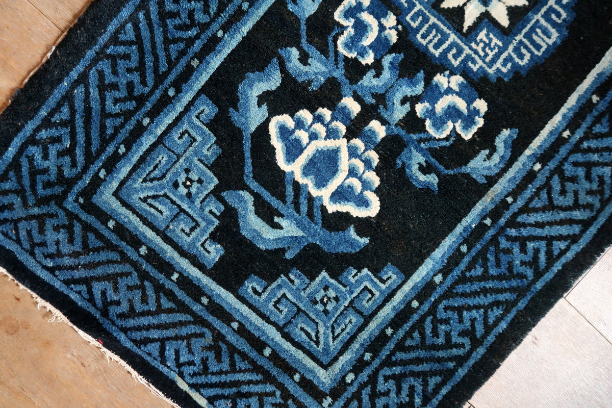 Large blue-and-ivory end blossom between angular geometric corner ornaments