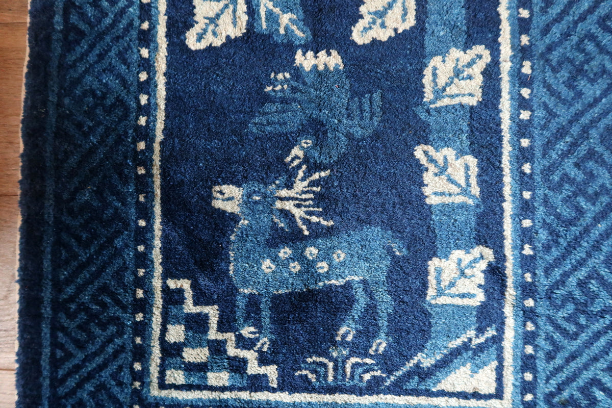 Spotted deer and smaller animal motif beside angular ivory foliage