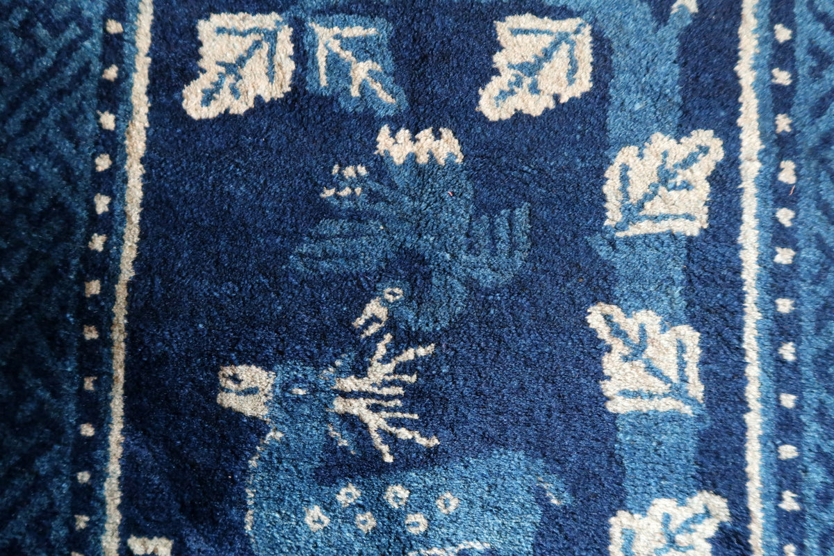 Smaller blue animal form among ivory leaves with visible pile wear and colour variation