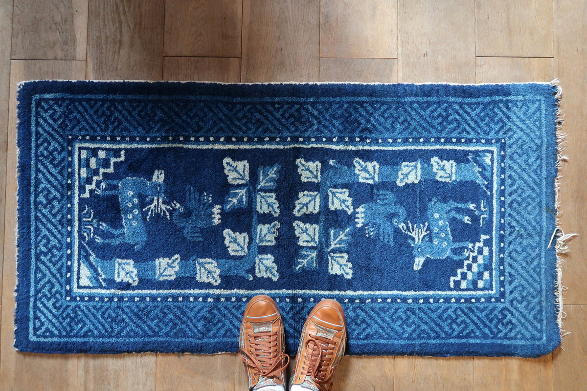 Overall horizontal view showing two deer, leafy stems and layered blue fretwork borders