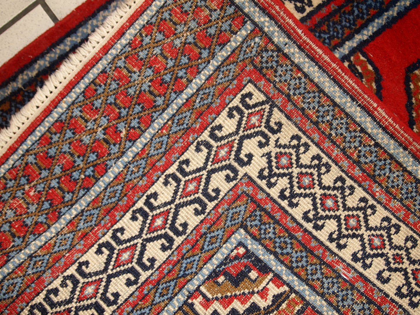 Handmade Indo-Mahal rug with vibrant red, white, and blue patterns.

