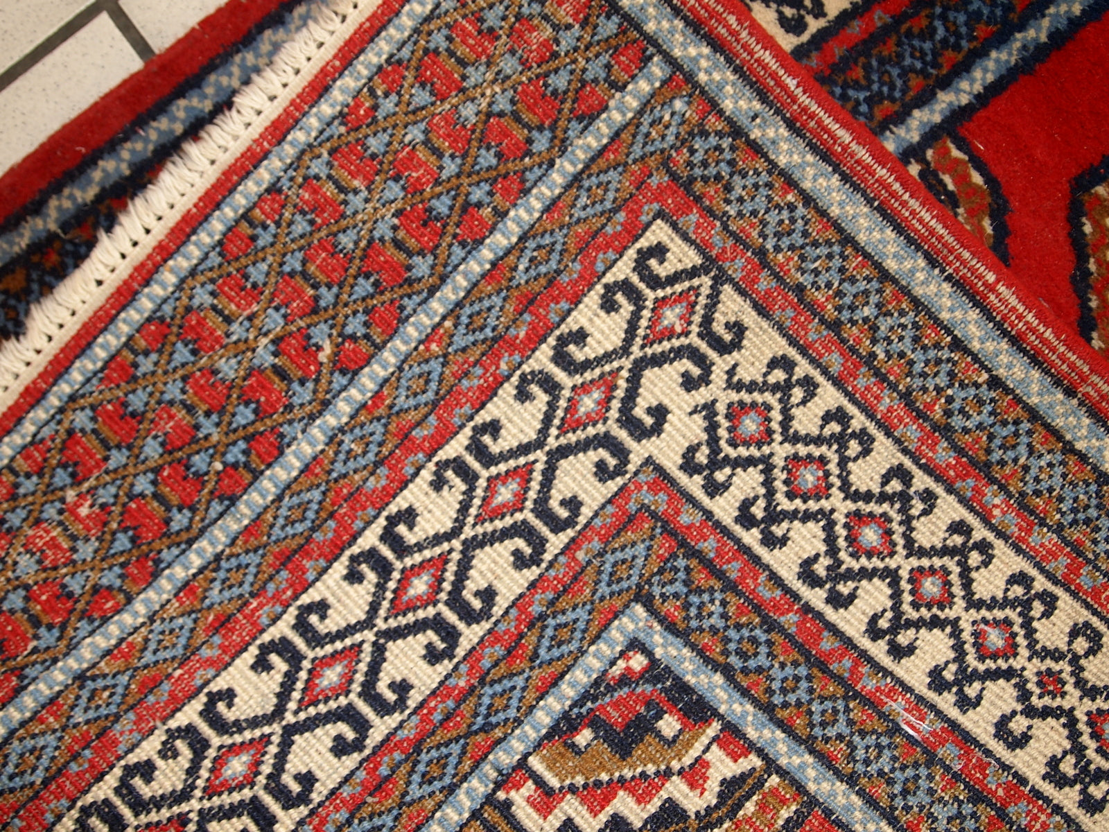 Handmade Indo-Mahal rug with vibrant red, white, and blue patterns.

