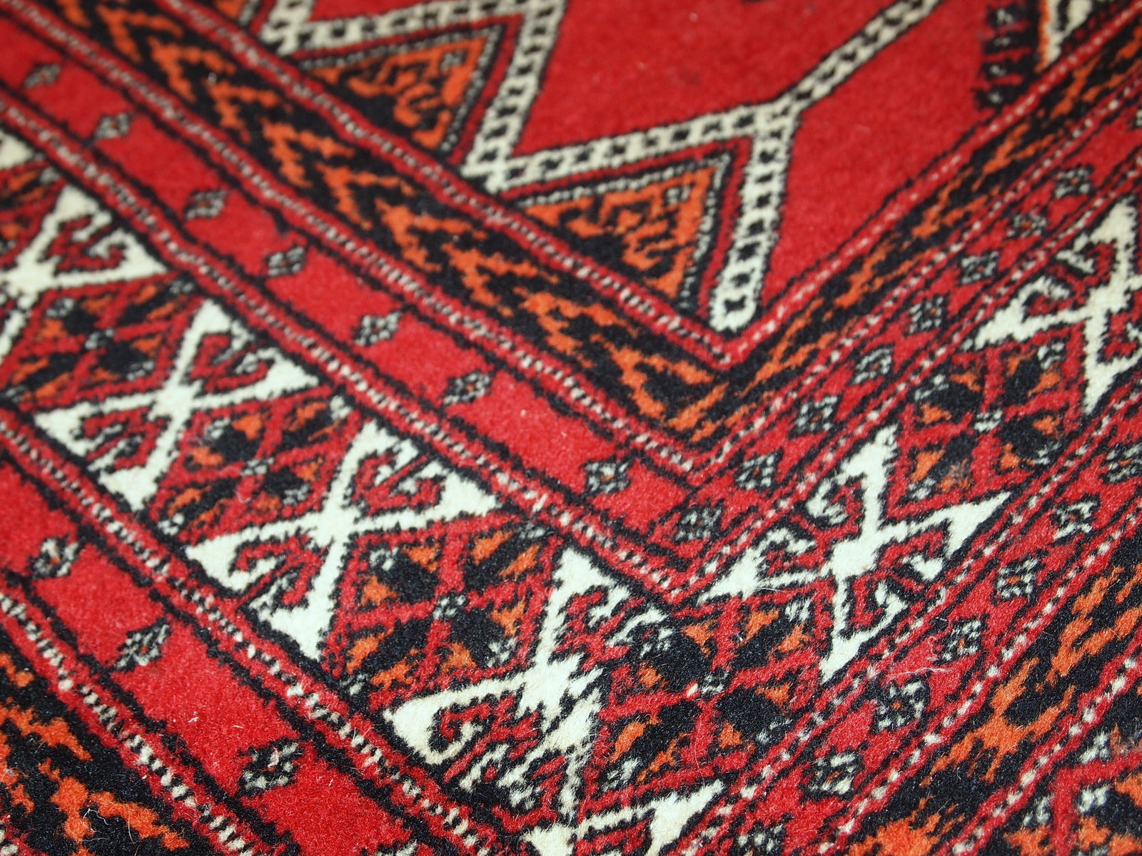 Distressed wool rug from Pakistan, showcasing its rich red and pink color scheme.

