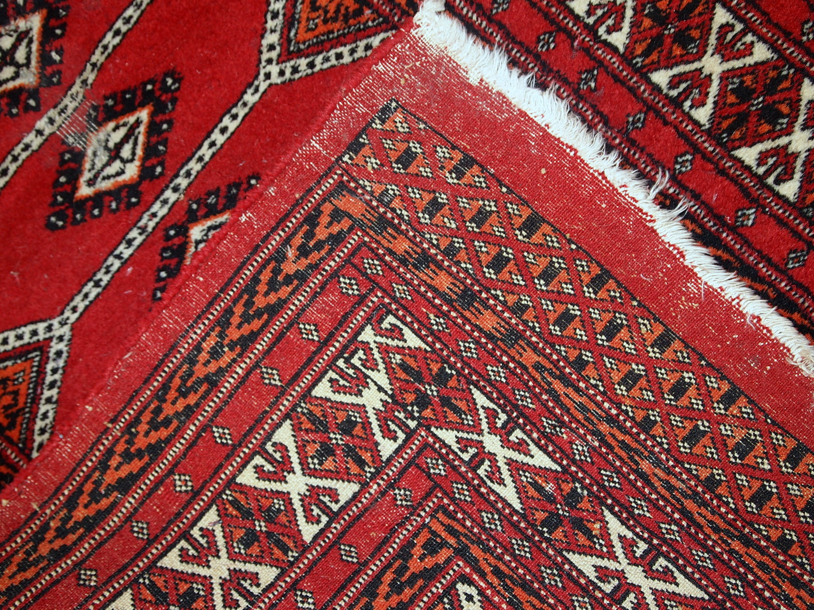 Handmade Pakistani Lahore rug featuring geometric patterns in red and orange.

