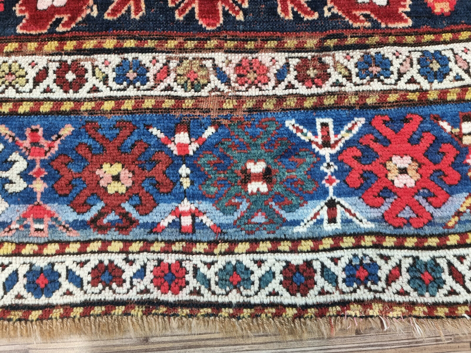 Antique Caucasian Kazak rug with visible wear and history
