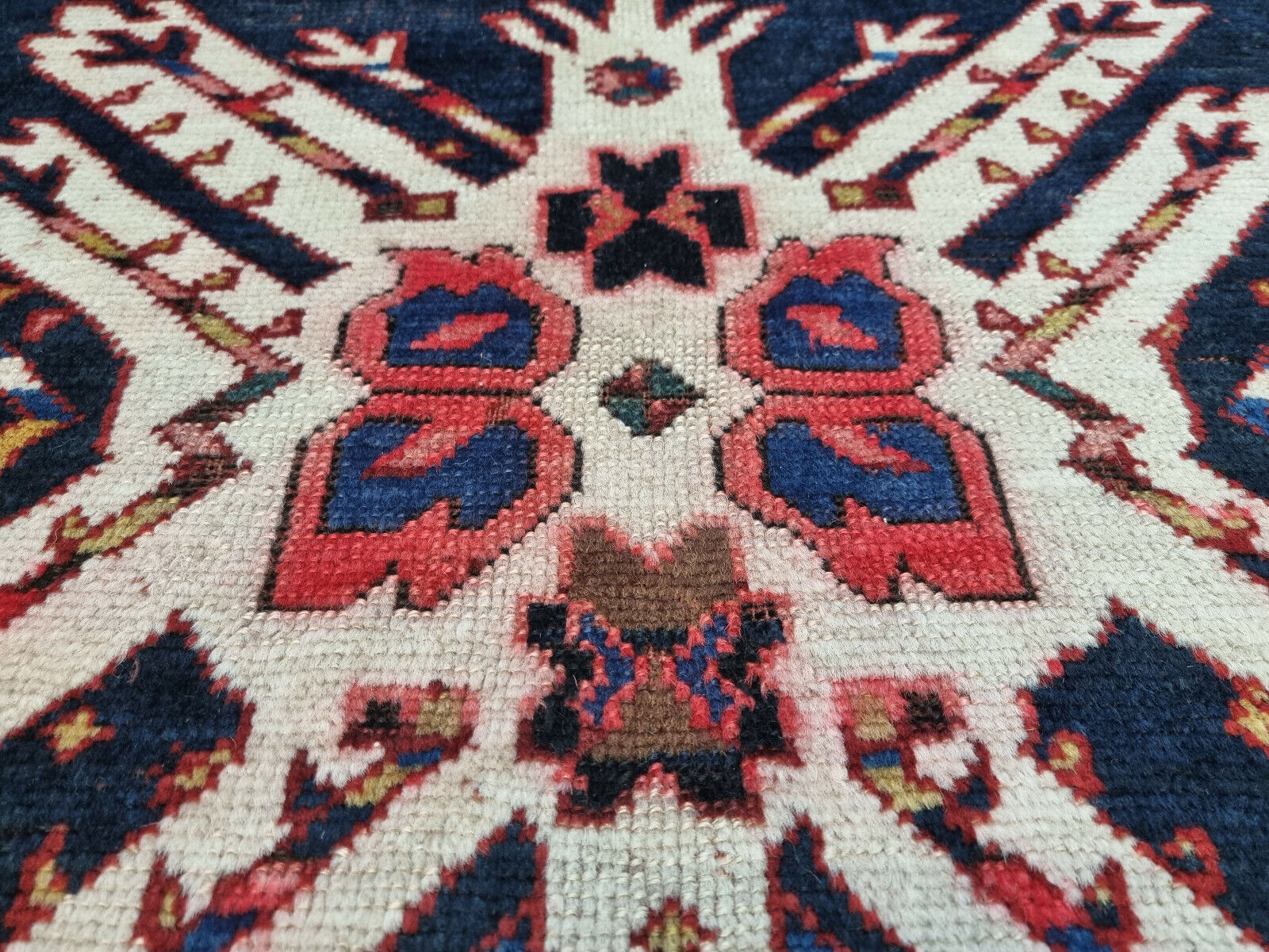 Geometric motifs in deep blue, red, and white on the Kazak rug
