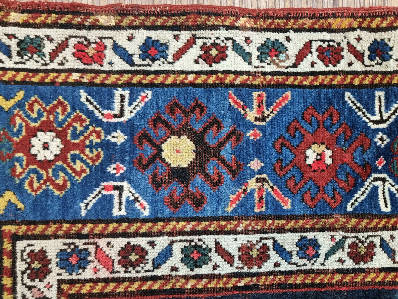Close-up of the three star-shaped central motifs in the Kazak rug
