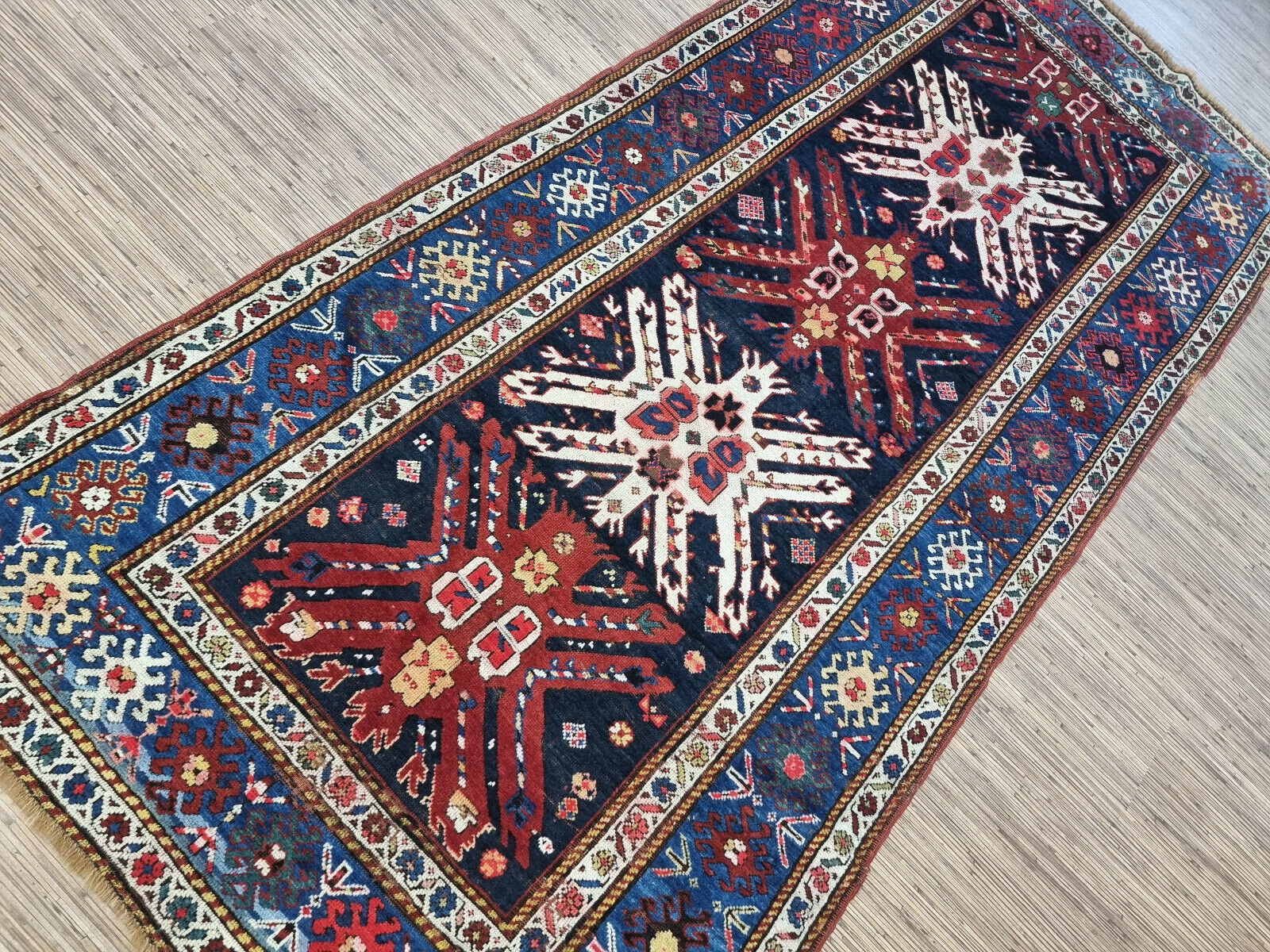Detailed view of the deep blue, red, and white colors on the Kazak rug
