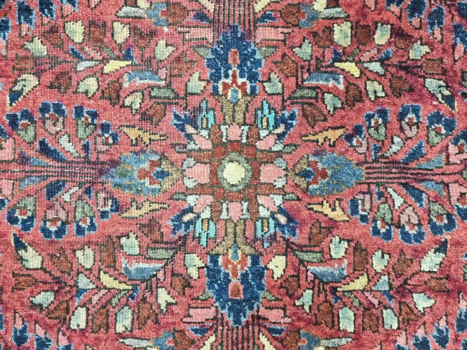 A full view of the rectangular antique Persian rug, displaying its elegant motifs
