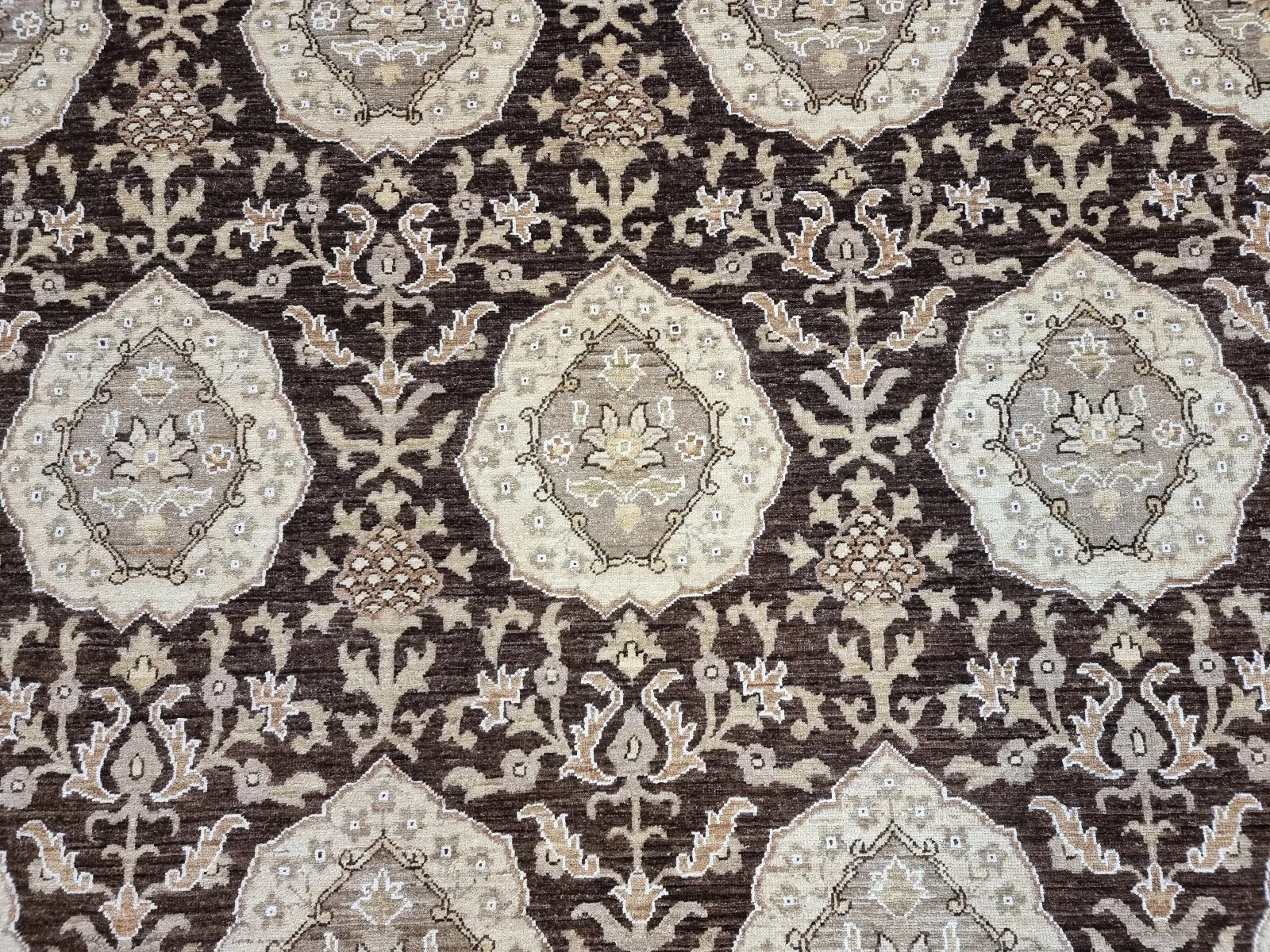Close-up detail of a large floral medallion in rich, dark brown wool.

