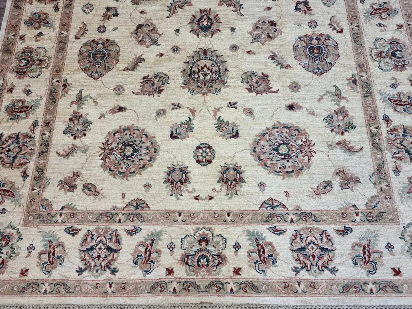 Close-up detail of a large floral medallion in soft brown and ivory wool.

