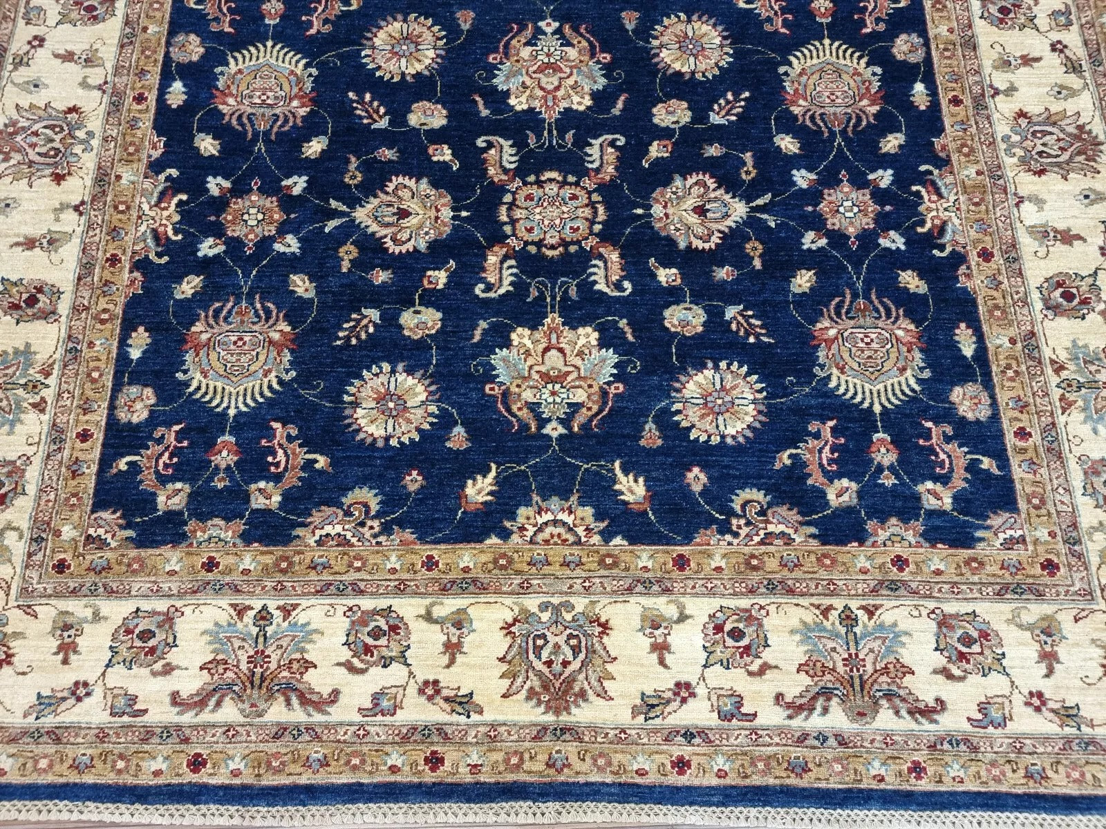 Close-up detail of a large floral medallion in deep navy blue wool.

