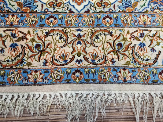 Close-up of a handmade Persian Isfahan carpet showing delicate traditional patterns, premium kork wool pile, and subtle sheen from the silk foundation.

