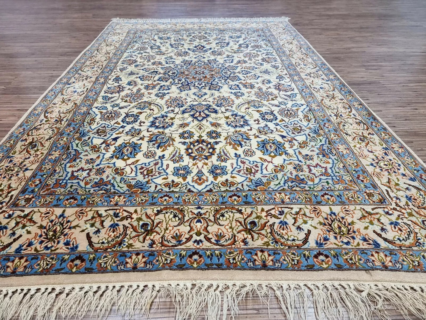 Antique-style Persian Isfahan carpet circa 1970s with a soft neutral palette, intricate floral details, and minor signs of wear along the edges consistent with age.


