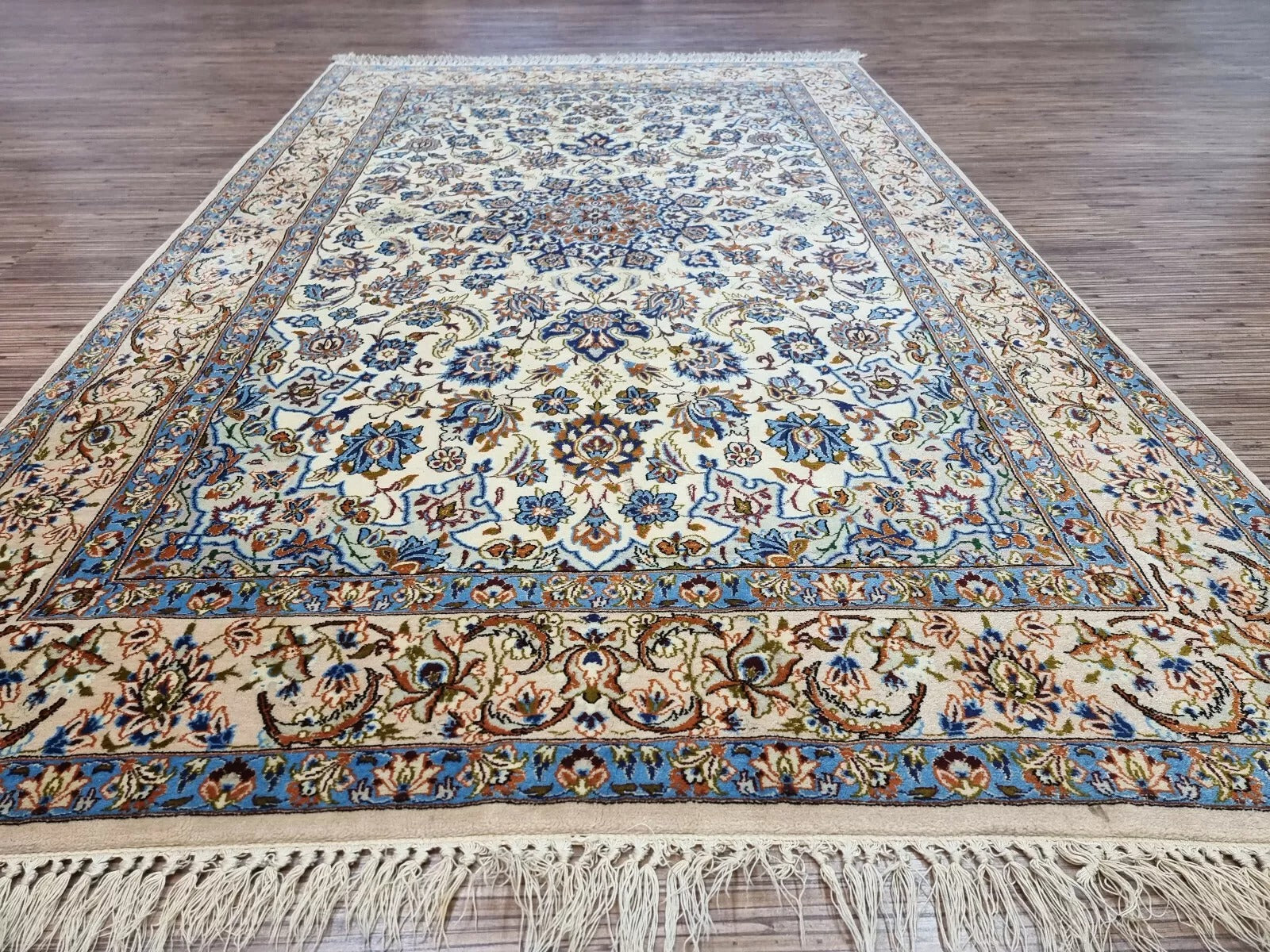 Antique-style Persian Isfahan carpet circa 1970s with a soft neutral palette, intricate floral details, and minor signs of wear along the edges consistent with age.

