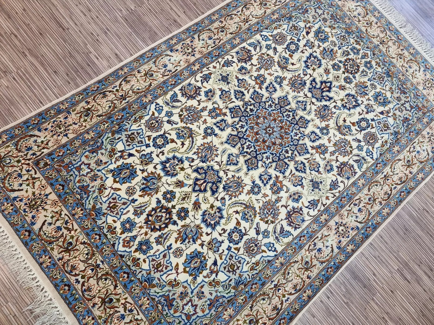 Close-up view of the corner and border detail on a vintage Isfahan rug, showing classic Persian motifs and the fine weave of kork wool on silk.


