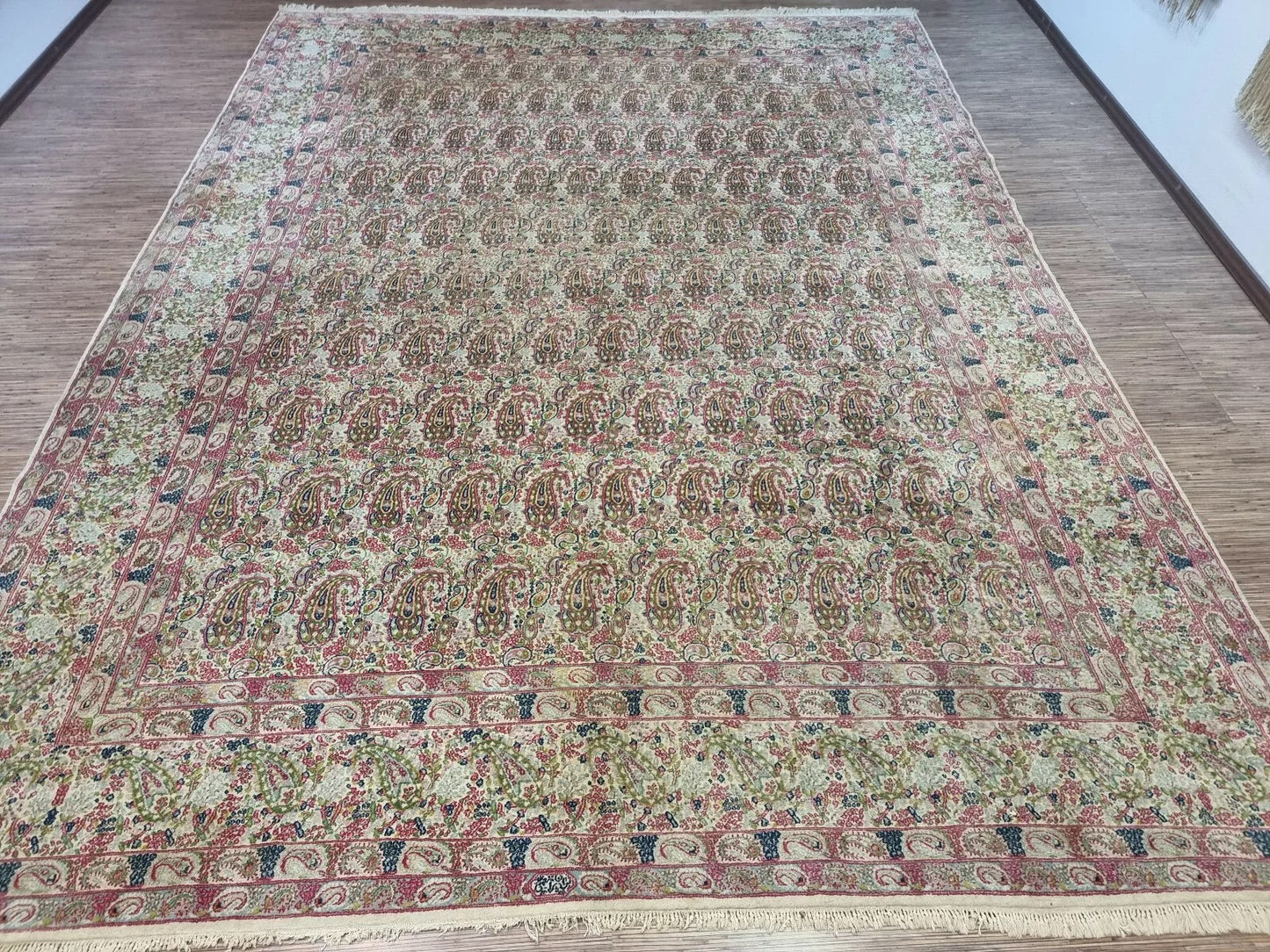 Full view of a vintage Persian Kerman rug laid flat, showing its rectangular shape, traditional border system, and soft neutral tones that blend with various interiors.

