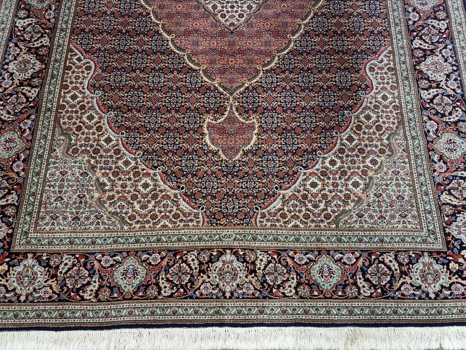 Close-up of a 1970s Persian Tabriz carpet showing intricate floral motifs and rich blue coloration on premium kork wool with a cotton foundation.

