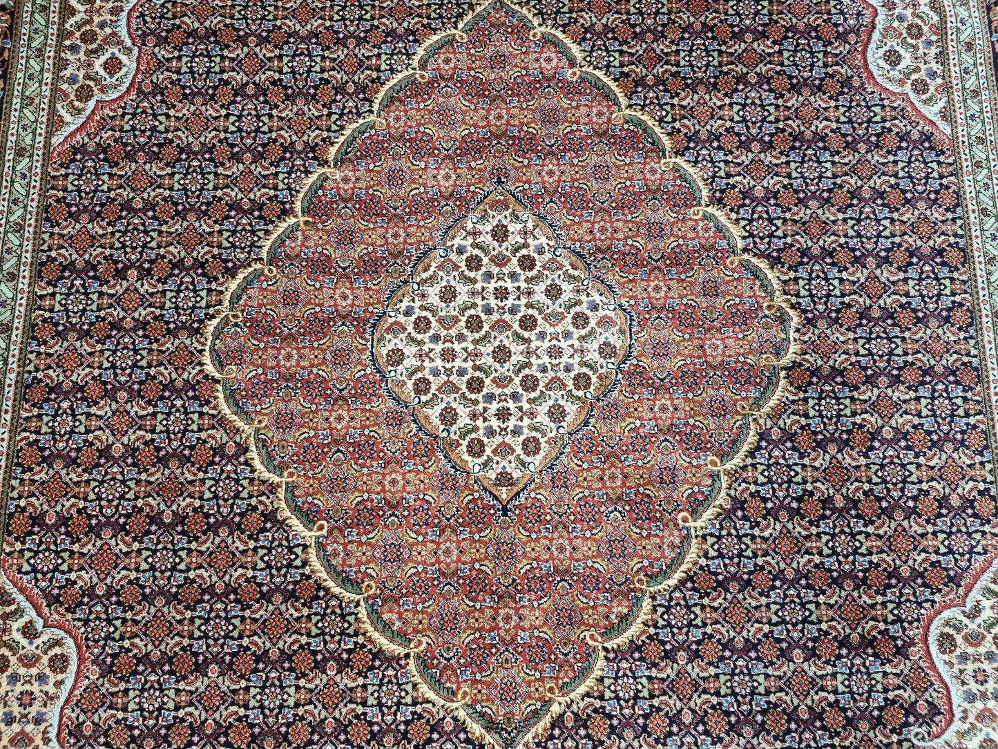 Detail of the central medallion and corner spandrels on a vintage Tabriz rug, showcasing the sophisticated floral design and high knot density characteristic of Tabriz weaving.

