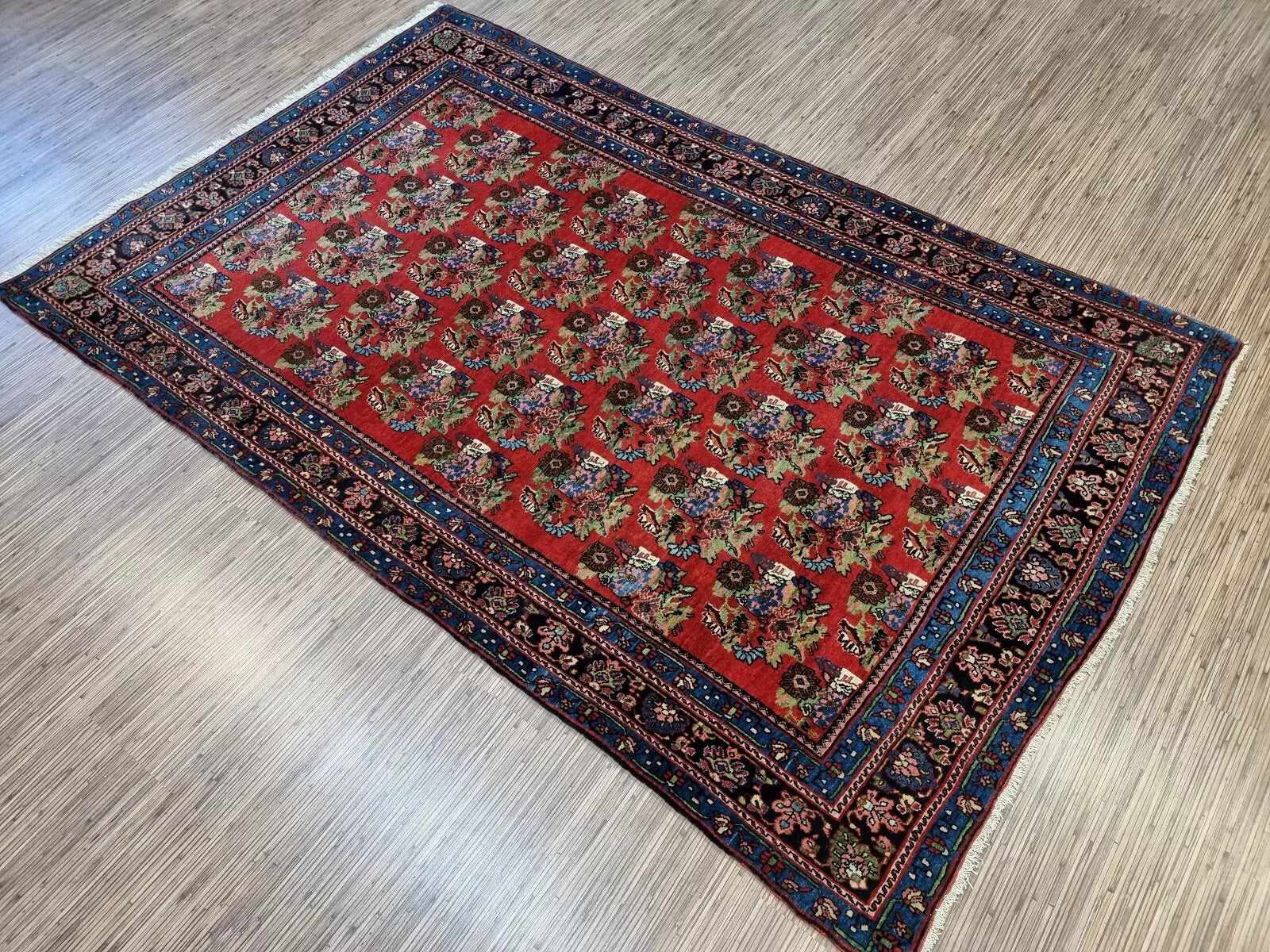 Antique Persian rug from Bidjar, hand-knotted in the early 1900s, featuring detailed floral sprays, rosettes, and vine scrolls in traditional Persian artistry.

