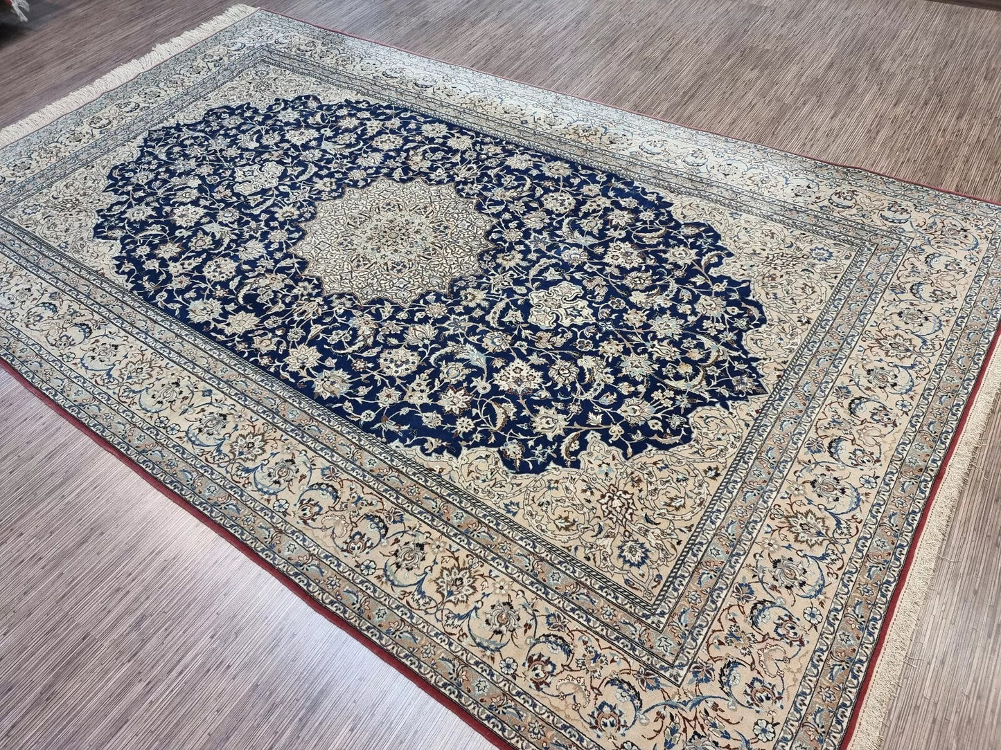 Full view of an antique hand-knotted Persian Nain rug laid flat, showing its rectangular shape, multiple borders, and traditional all-over floral pattern with an ivory field.

