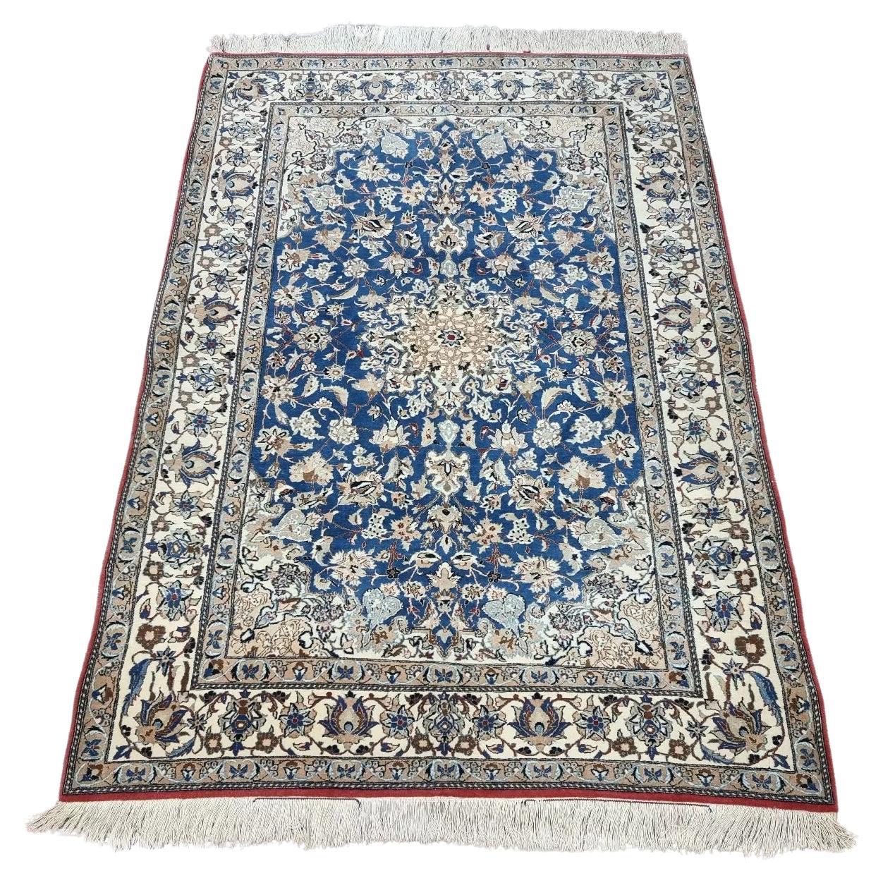 Full view of an antique Persian Nain rug from the 1920s, featuring a soft ivory field with intricate floral medallions and arabesques, hand-knotted with approximately 800,000 knots per square meter in kork wool on a cotton foundation.

