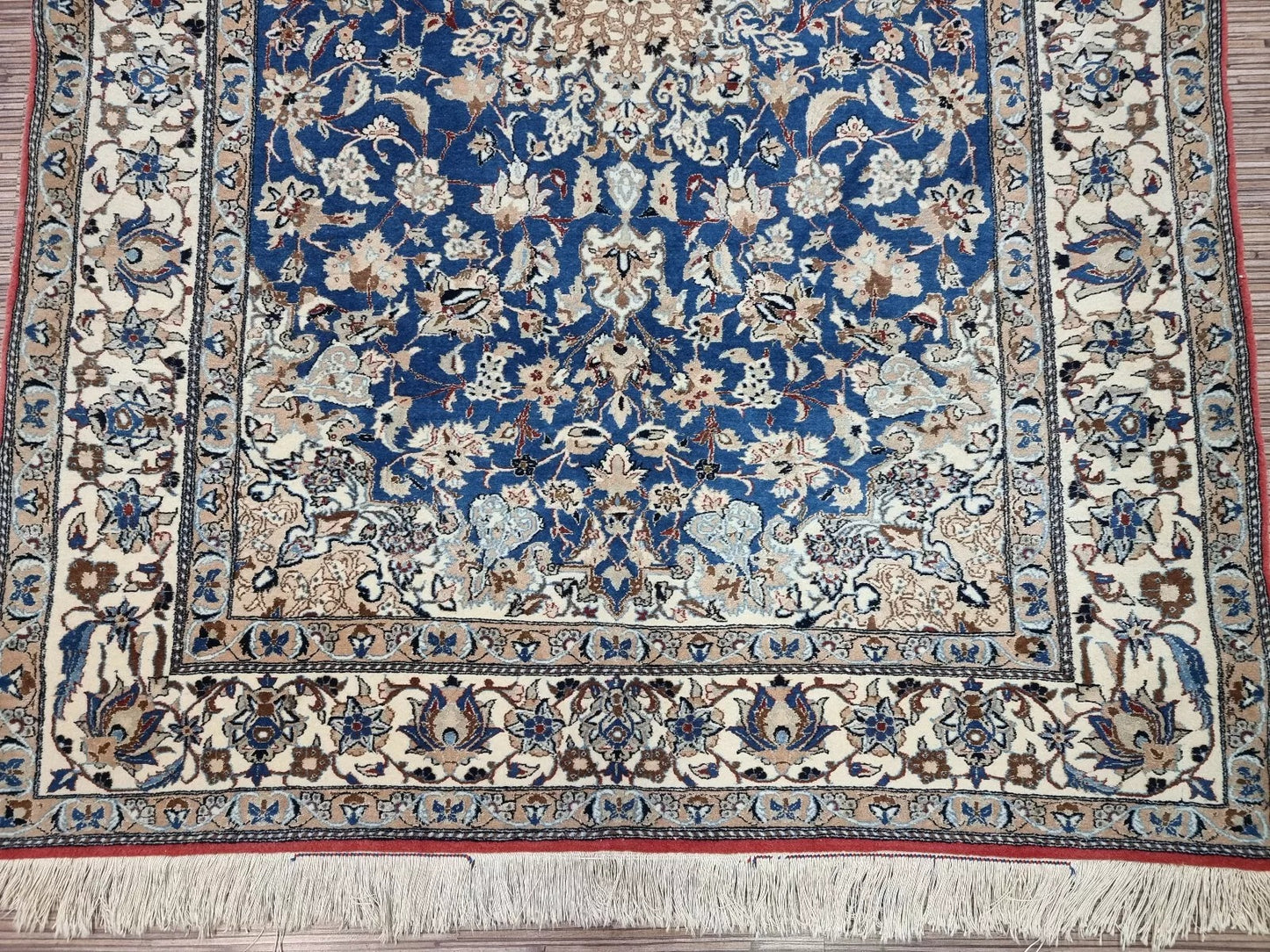 Detail of the central medallion on a vintage Persian Nain rug, showcasing the intricate floral and vine motifs typical of Nain craftsmanship, with soft ivory and navy blue coloration.

