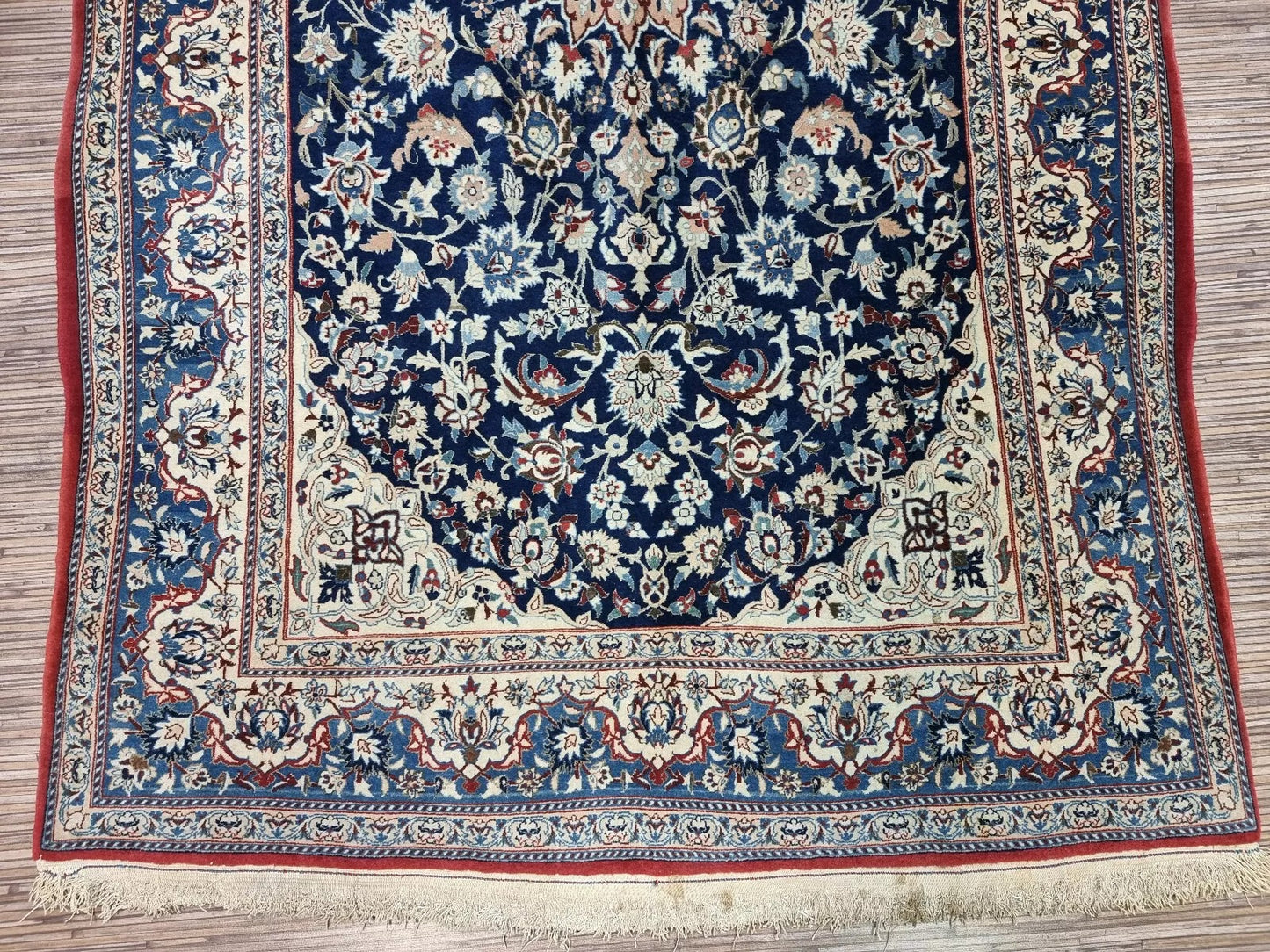 Detail of the central medallion on a vintage Persian Nain rug, showcasing intricate floral and vine motifs typical of Nain craftsmanship, with soft ivory and navy blue coloration.

