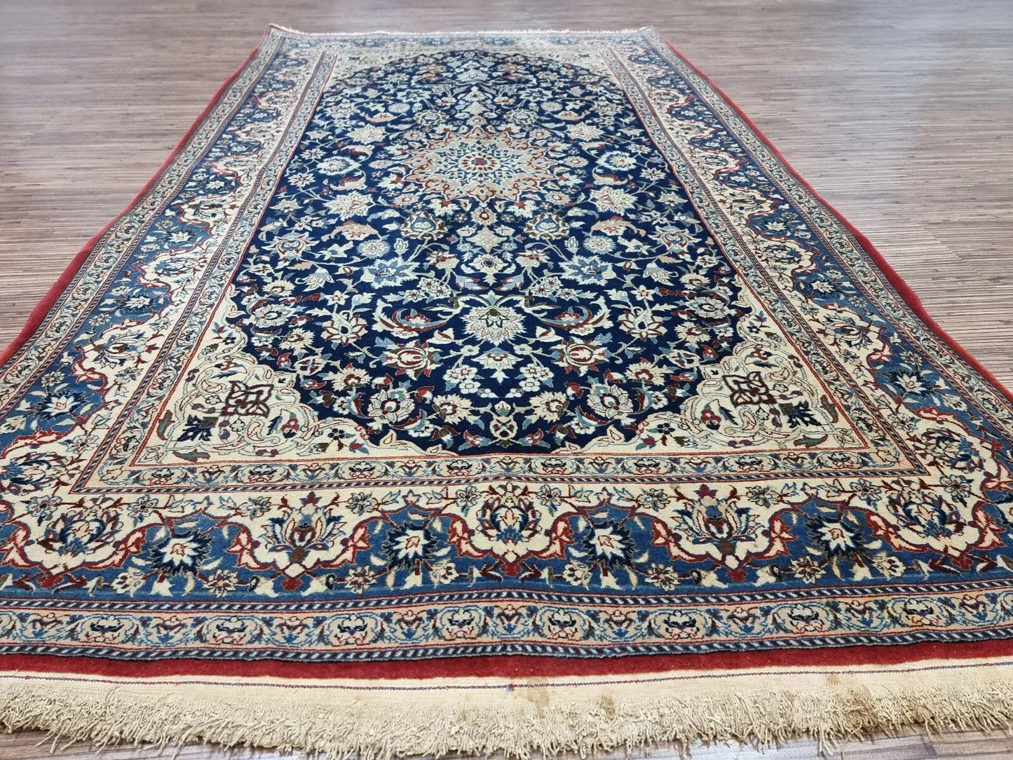 Collector-quality antique Persian Nain 6La Tudeshk rug circa 1920s with an ivory field, navy blue medallion, floral corner spandrels, and a harmoniously patterned border system.

