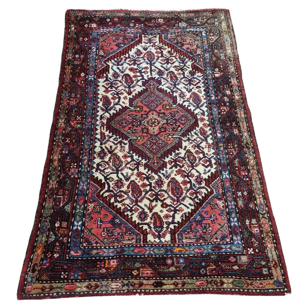 Full view of a vintage Persian Hamadan rug from the 1950s, featuring a rich crimson field with a central medallion and intricate floral motifs, hand-knotted in wool on a cotton foundation.

