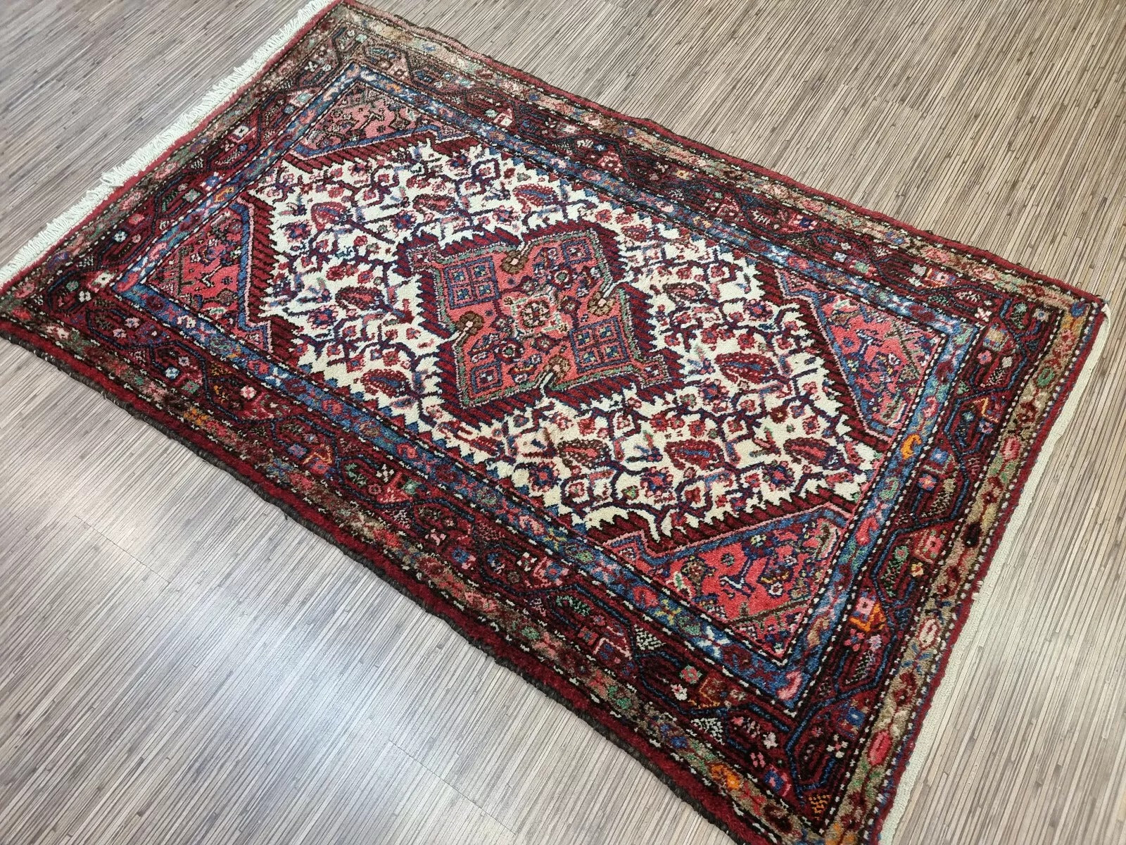 Collector-quality vintage Persian Hamadan rug circa 1950s with a crimson field, navy blue medallion, floral corner spandrels, and a patterned border system.

