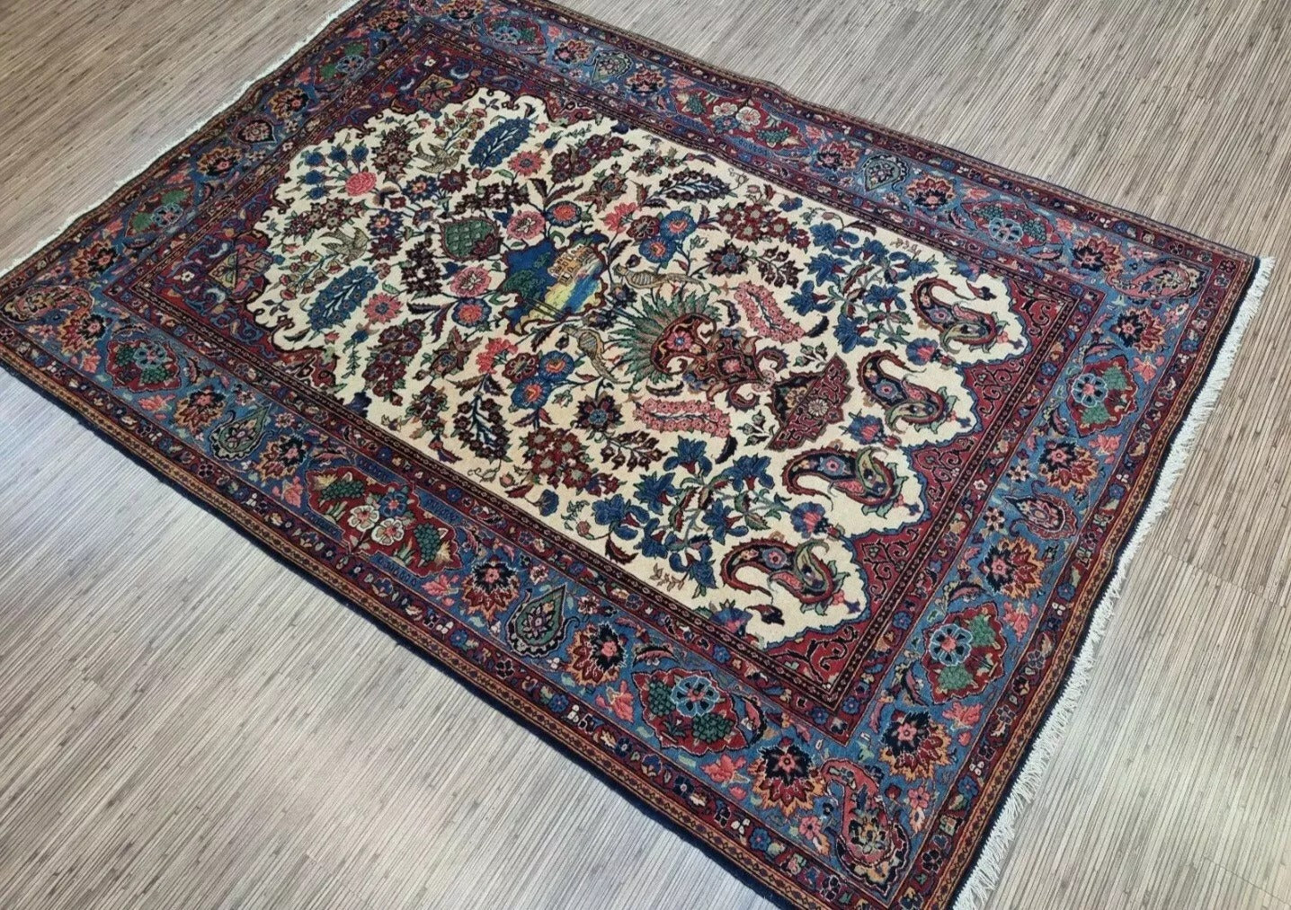 Full view of an antique hand-knotted Persian Kashan rug laid flat, showing its rectangular shape, multiple borders, and classic all-over floral pattern with a central medallion.

