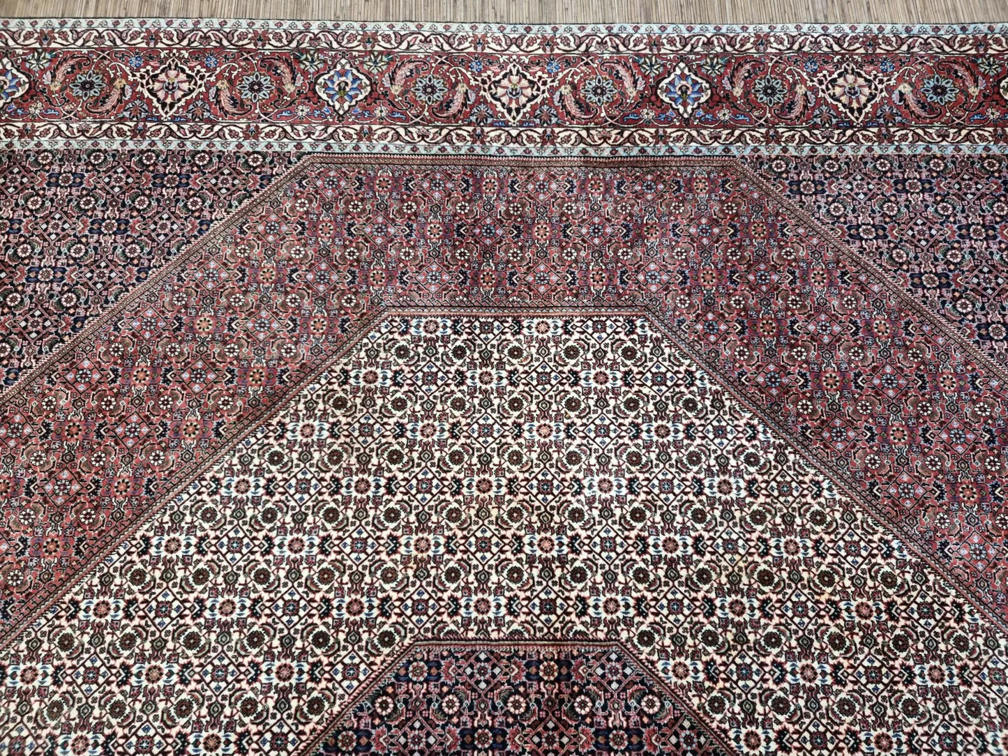 Close-up of a 1970s Persian Bidjar carpet showing the dense knotting and detailed floral motifs in rich red, navy, ivory, and gold tones, demonstrating the superior craftsmanship for which Bidjar rugs are renowned.

