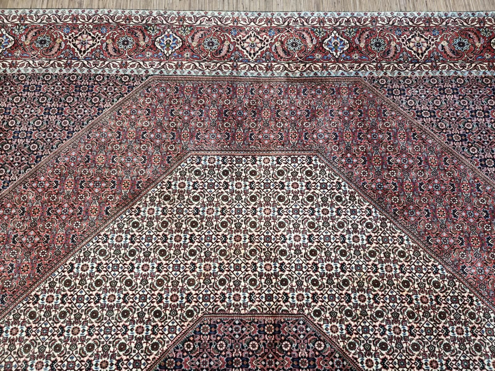 Close-up of a 1970s Persian Bidjar carpet showing the dense knotting and detailed floral motifs in rich red, navy, ivory, and gold tones, demonstrating the superior craftsmanship for which Bidjar rugs are renowned.

