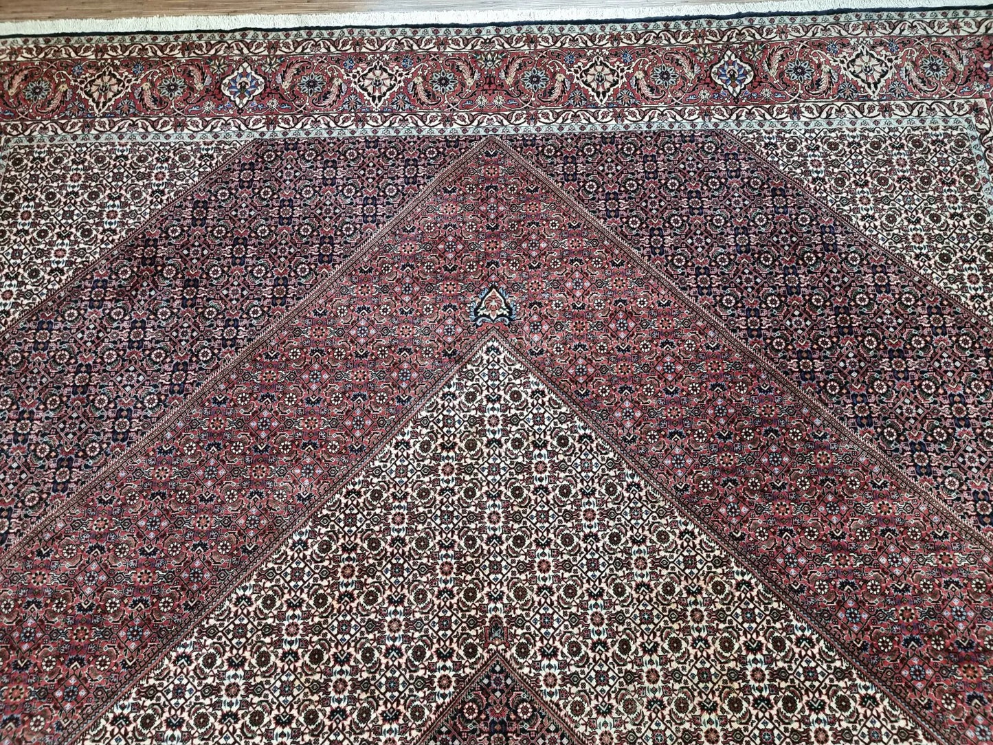 Full perspective of a vintage Persian Bidjar rug displayed in a large room, demonstrating its substantial 9.8 × 12.9 foot size as a statement piece that adds warmth and character.


