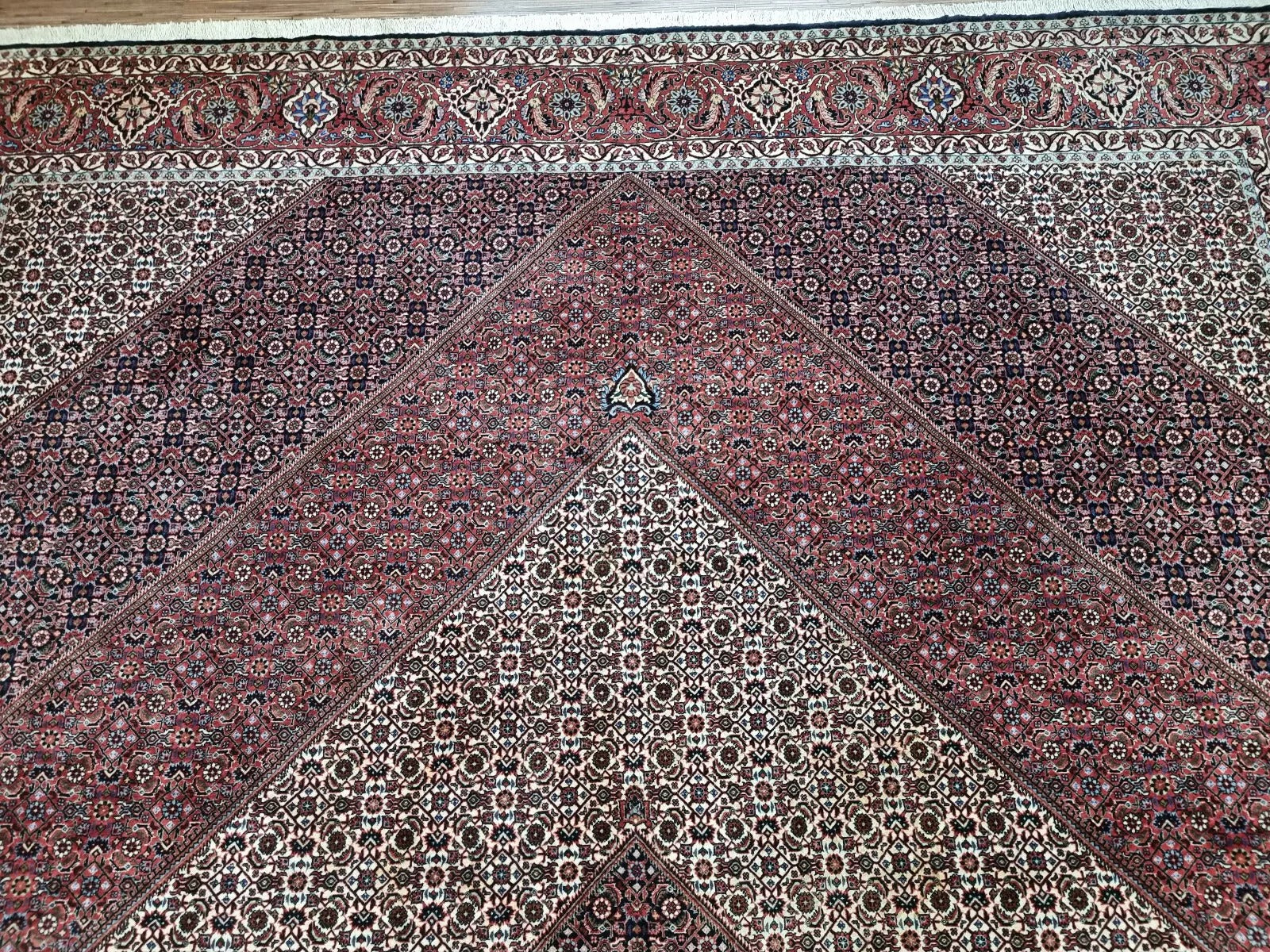 Full perspective of a vintage Persian Bidjar rug displayed in a large room, demonstrating its substantial 9.8 × 12.9 foot size as a statement piece that adds warmth and character.

