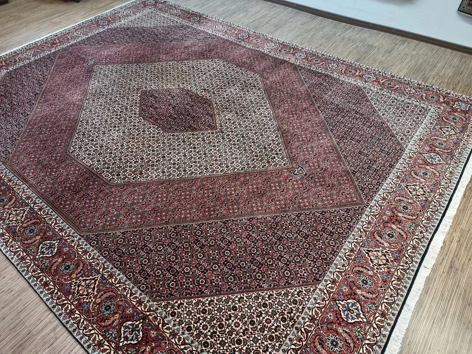 Full view of a vintage hand-knotted Persian Bidjar rug laid flat, showing its rectangular shape, multiple borders, and classic all-over floral pattern with a prominent central medallion.

