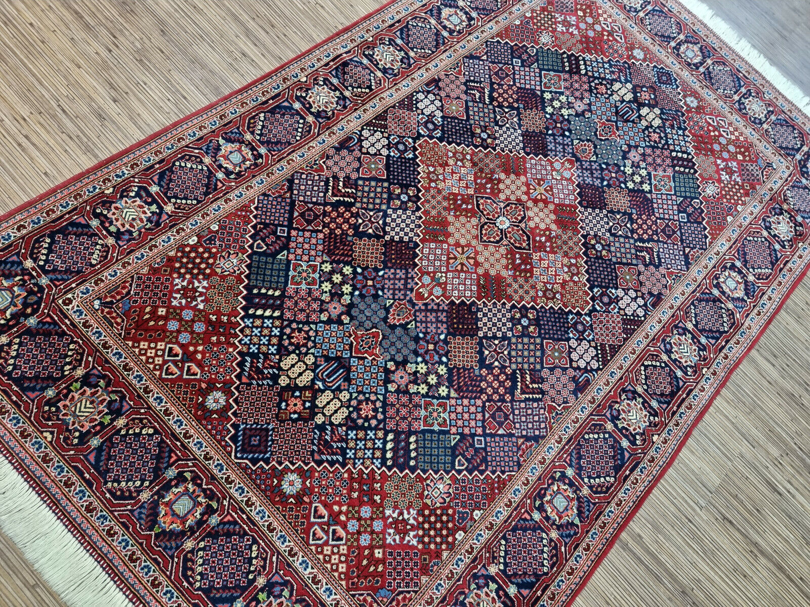 Close-up of a 1950s Persian Kashan carpet showing the detailed geometric medallion and corner spandrels with floral and arabesque patterns in vibrant blue, ivory, and complementary accent tones.

