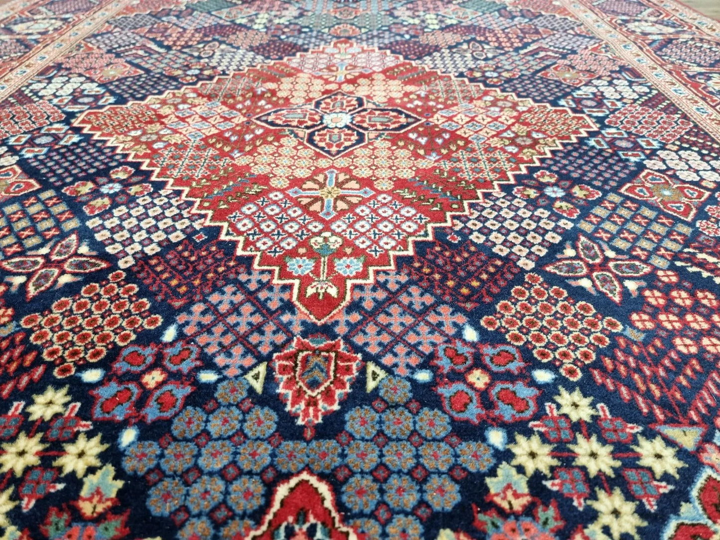 Detail of the central medallion on a vintage Persian Kashan rug, showcasing intricate geometric and floral motifs typical of Kashan craftsmanship, with dominant blue hues and ivory accents.

