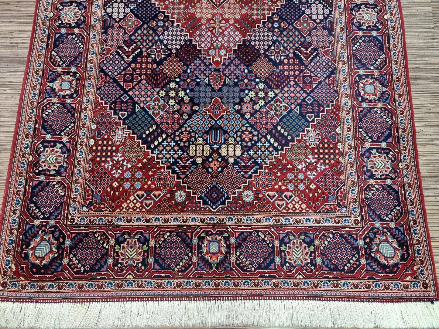 Full perspective of a vintage Persian Kashan rug displayed in a room, demonstrating its 4.4 × 7.3 foot size as an elegant accent piece for classic or modern interiors.


