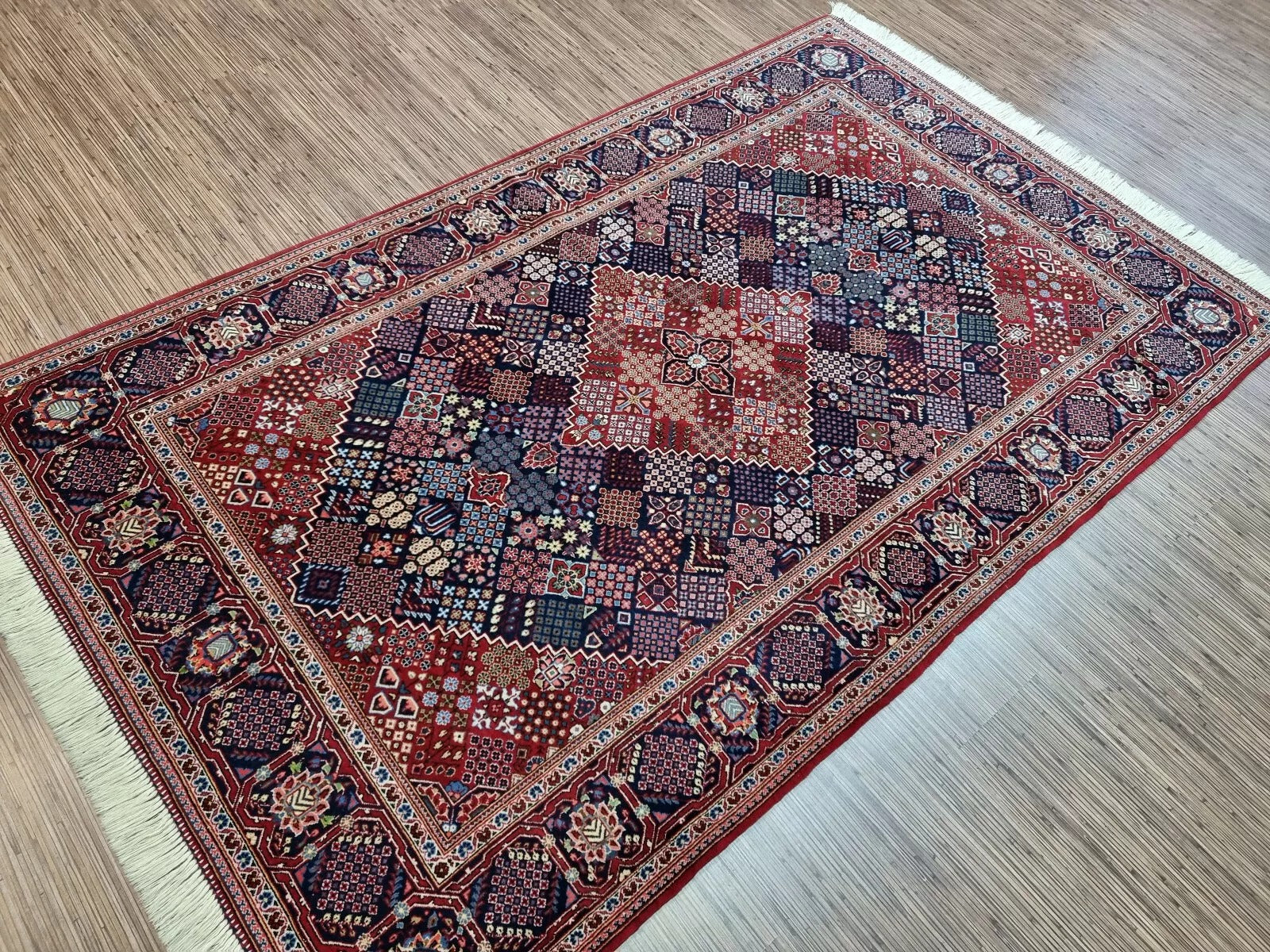 Full view of a vintage hand-knotted Persian Kashan rug laid flat, showing its rectangular shape, multiple borders, and classic geometric pattern with a prominent central medallion.

