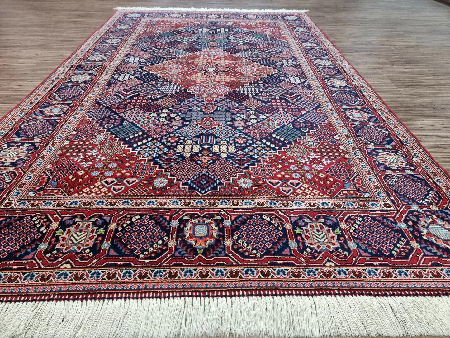Detail of the border on a 1950s Persian Kashan carpet, revealing repeated floral and geometric motifs in blue, ivory, and gold with elegant symmetry and fine wool texture.


