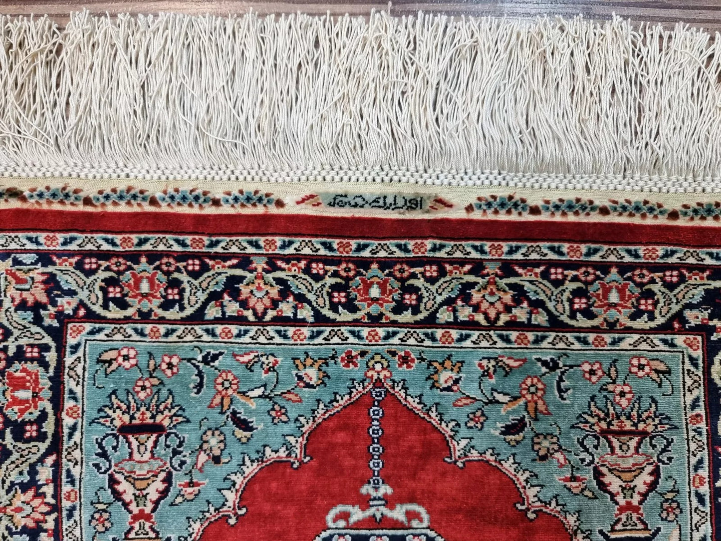 Detail of the central medallion on a miniature Hereke silk rug, showcasing intricate floral arabesques and vine scrolls executed at an ultra-fine knot density of 13×13 knots per square centimeter.

