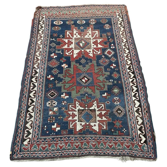 Full top view of the antique Caucasian Lezgi rug showing the central medallion on a blue field.

