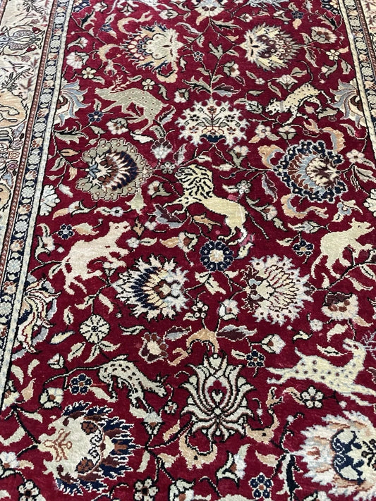Intricate palmette and vinery details on burgundy field

