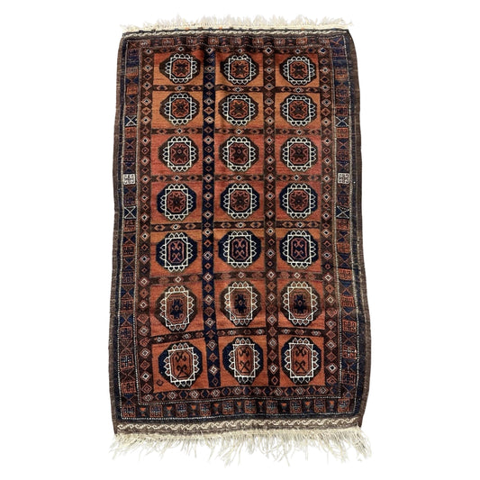 Full front view of the antique Afghan Baluch rug showing its full geometric design.

