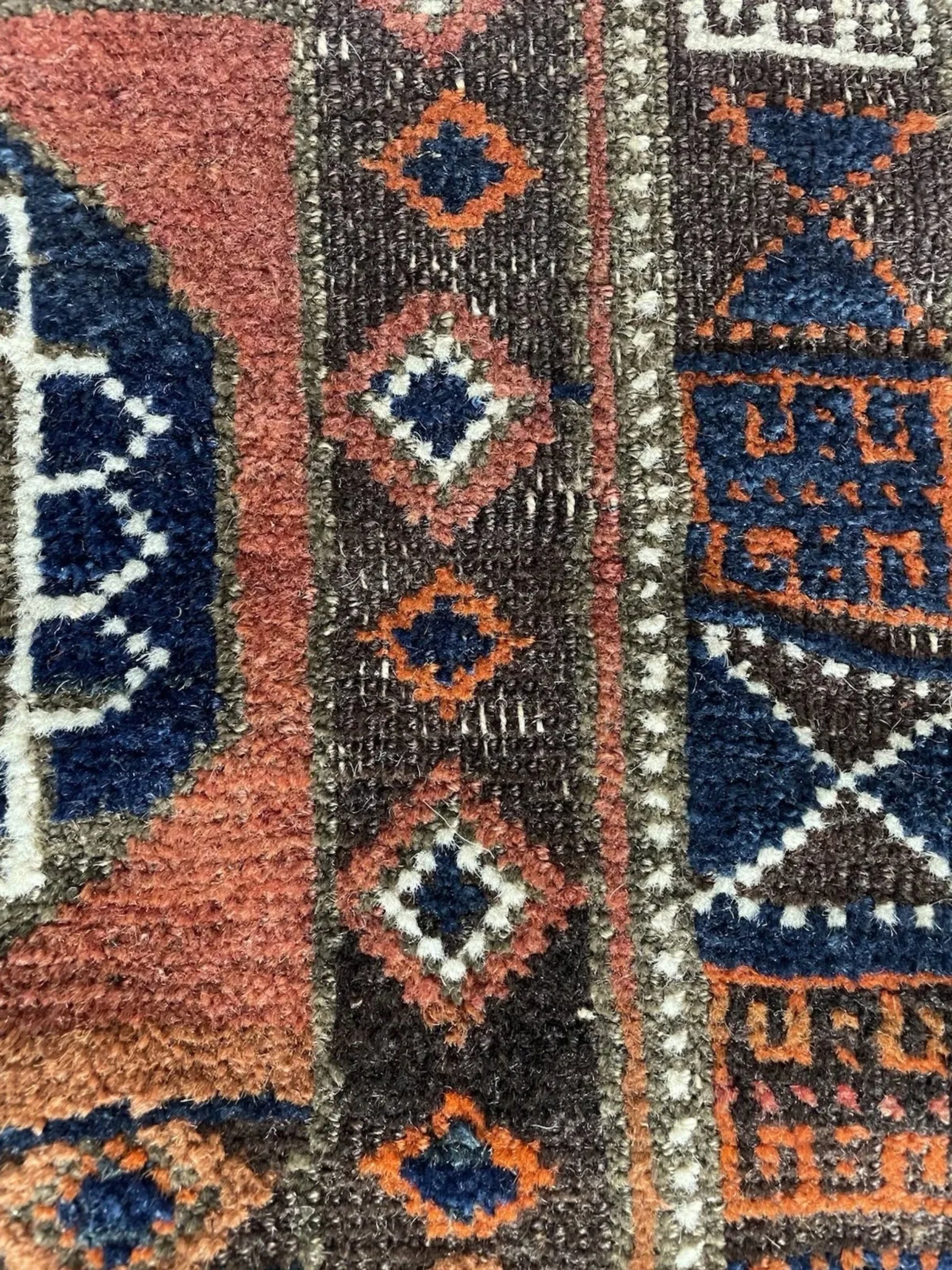 The Baluch rug displayed on a wooden floor to showcase its scale.

