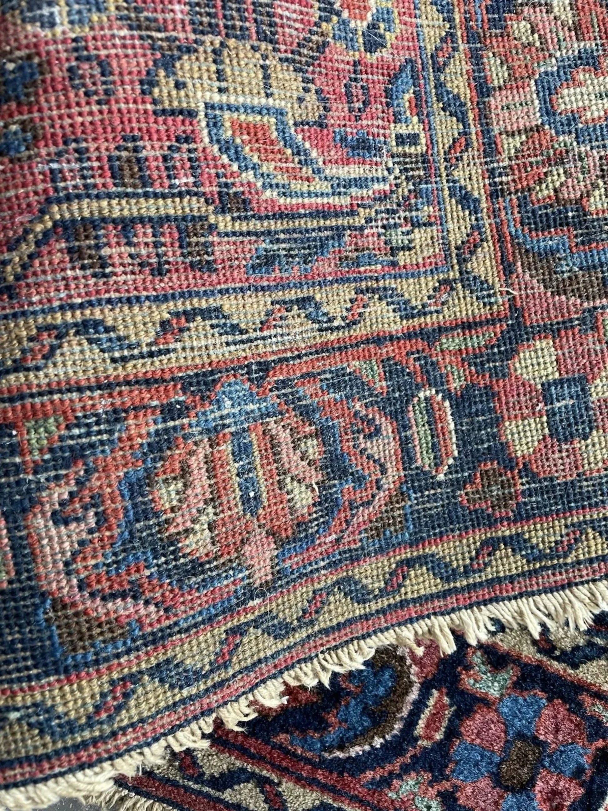Close-up detail of the herati pattern and stylized palmettes on the burgundy field.

